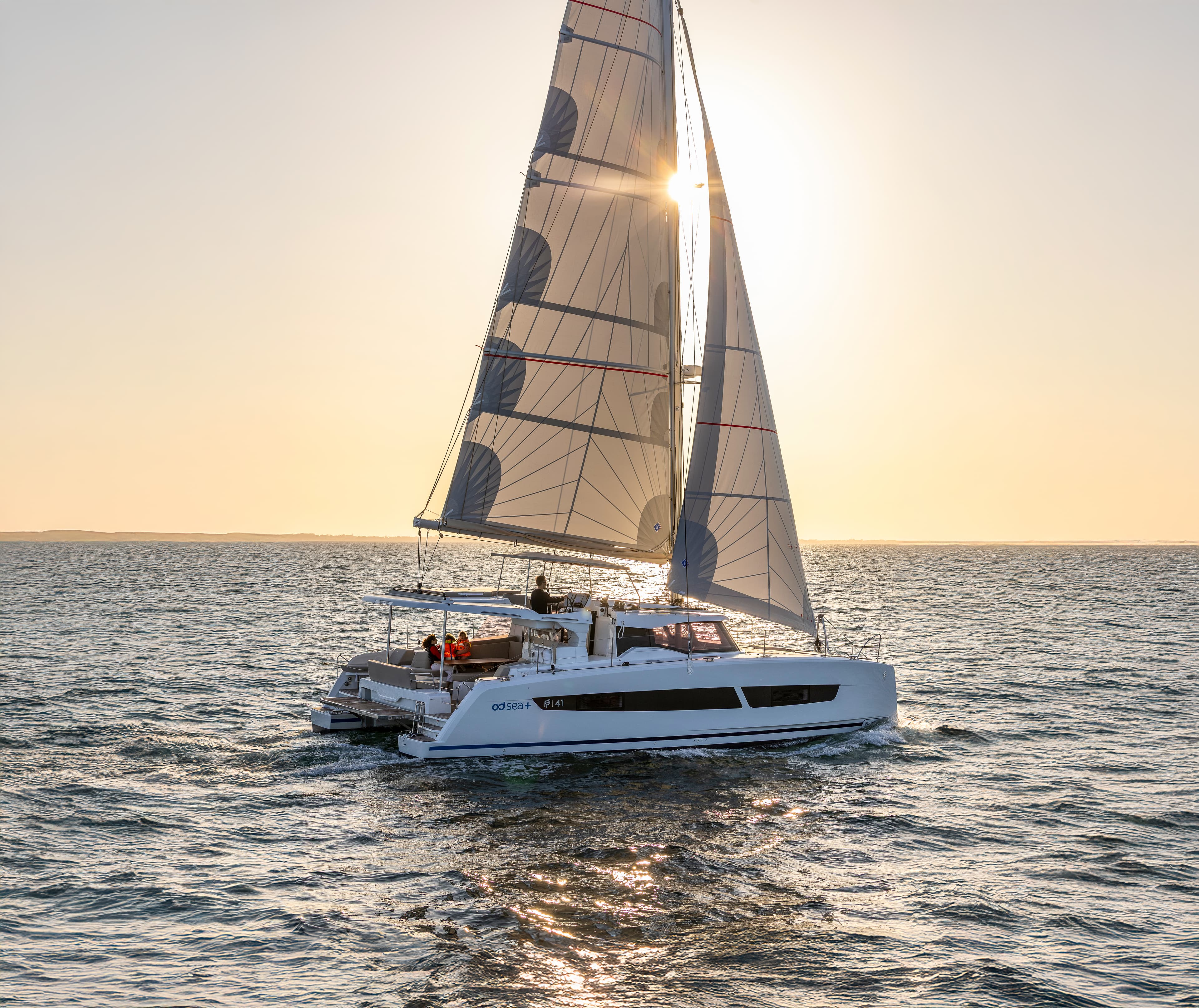 Katamaran ligger ankrad i vik i solnedgång.