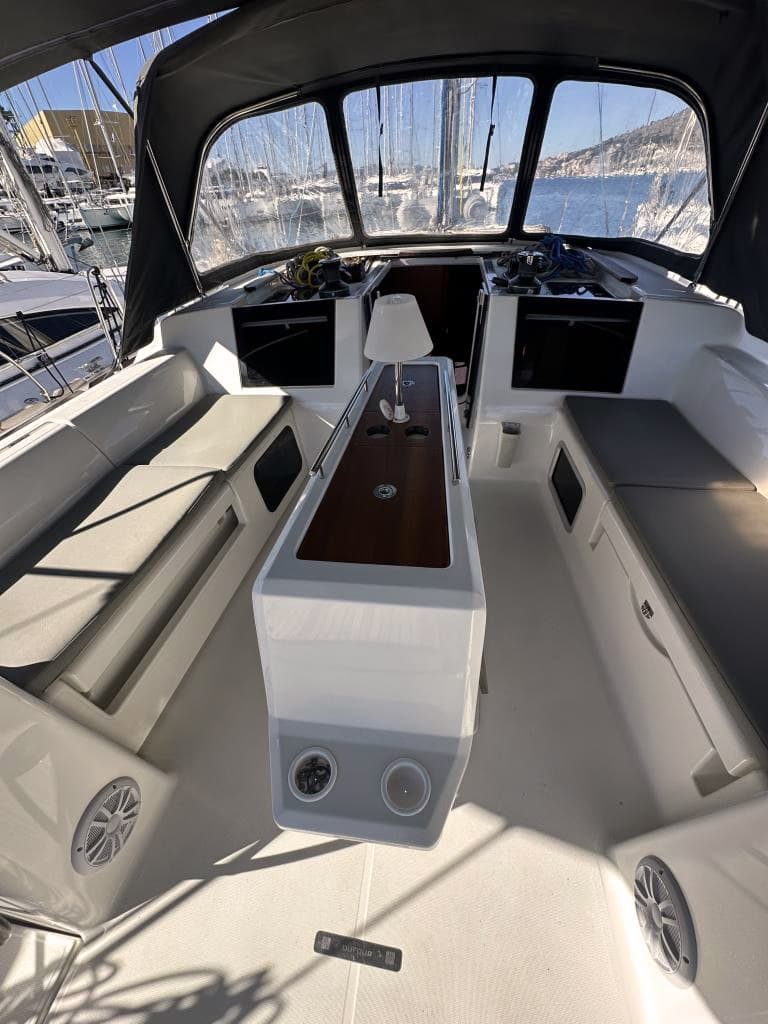 Cockpit med lampe, bord og bænke med puder på enkeltskrogs båden Dufour 530.