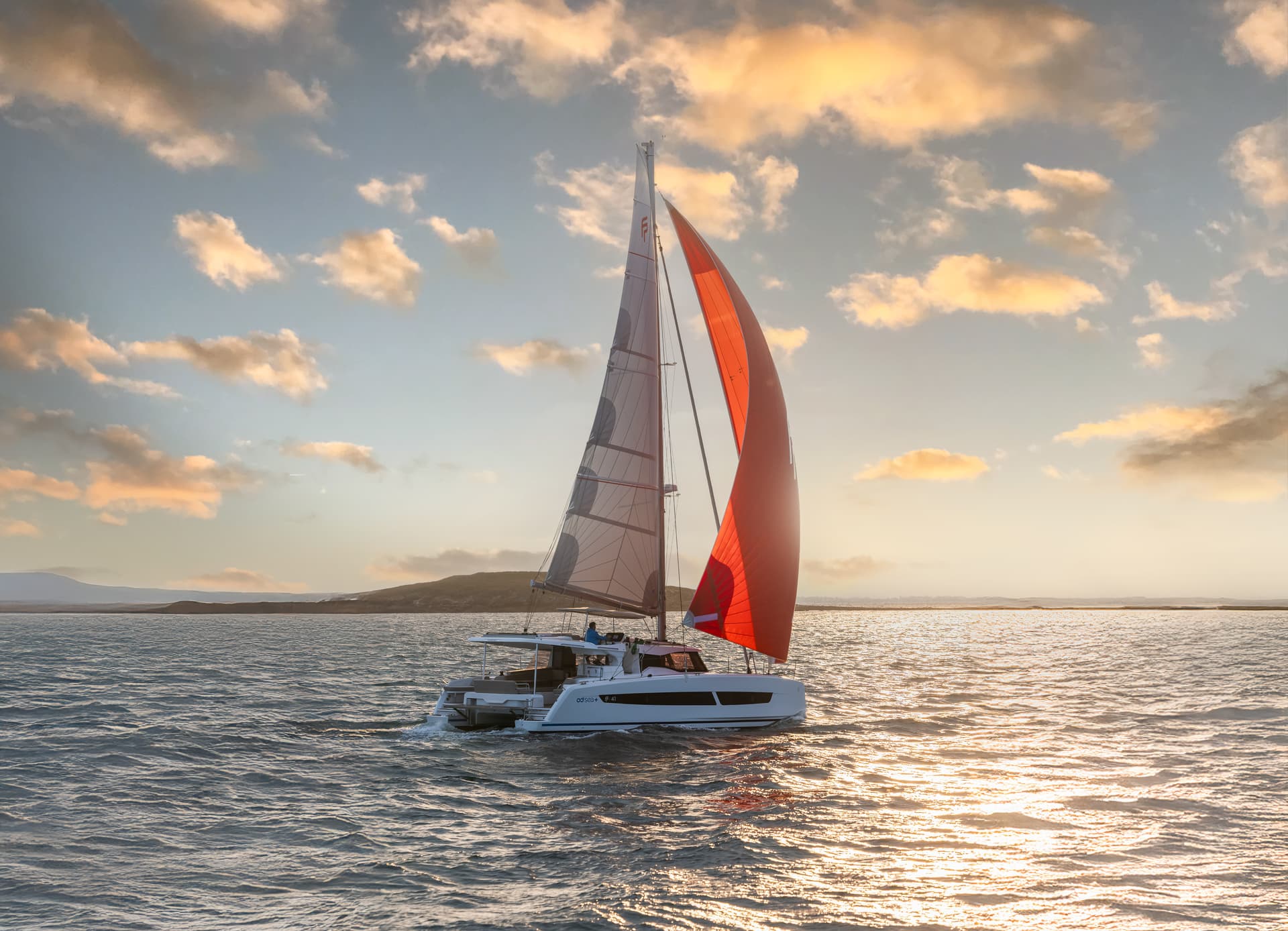 Katamaran ligger ankrad i vattnet vid solnedgång.